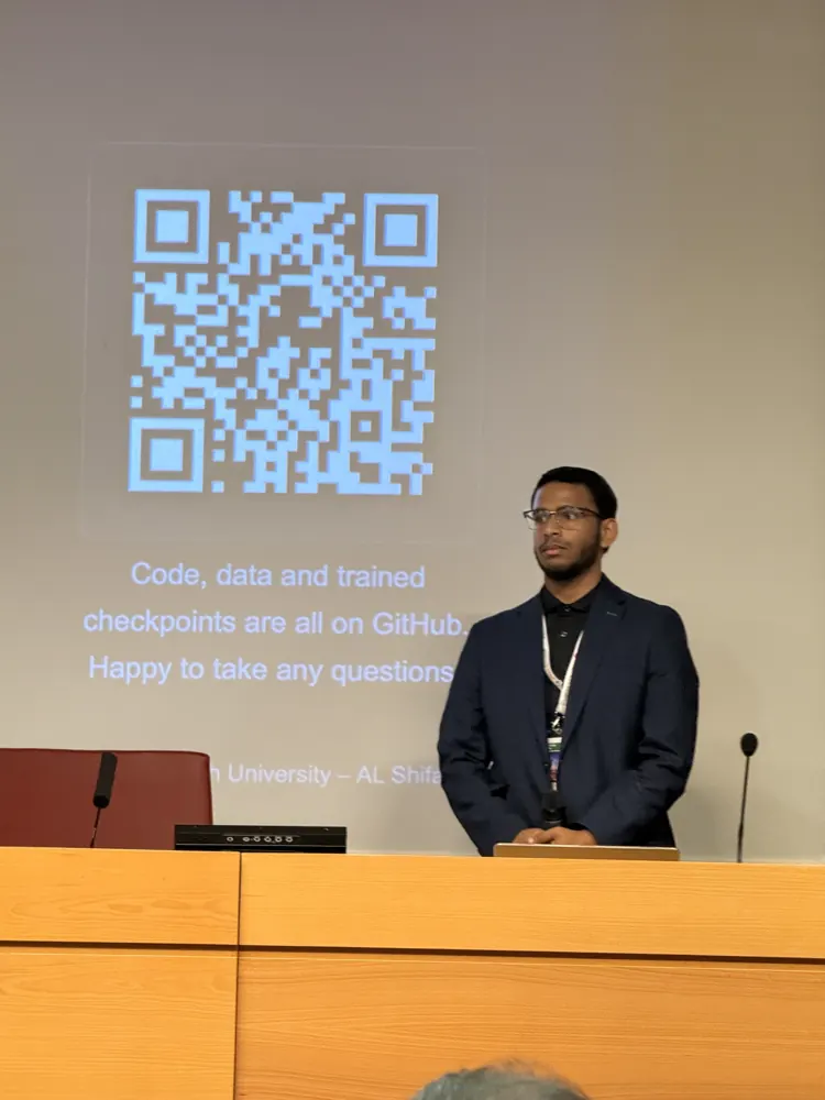 Al Shifan at the podium on the last slide, with a QR code to the GitHub repository